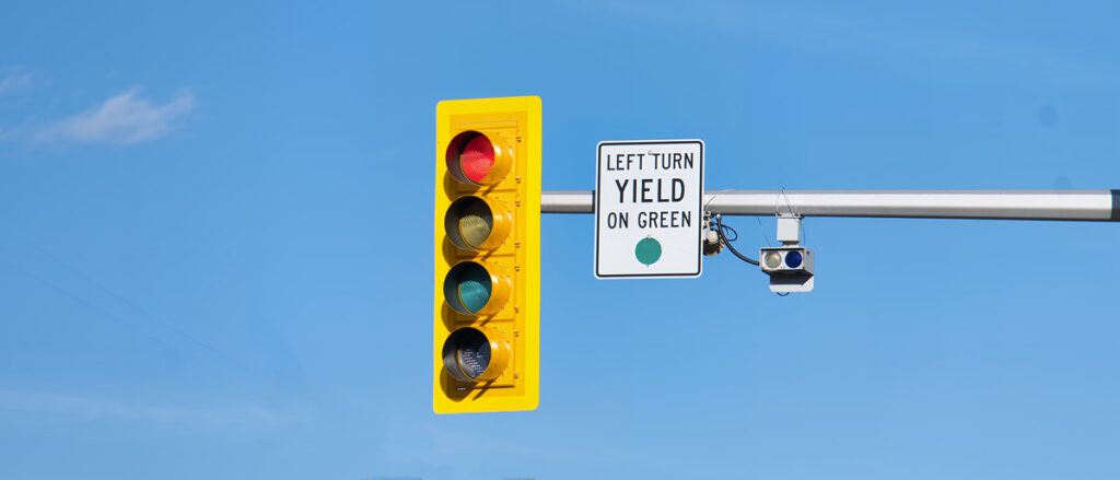 Close-up of a traffic signal and regulatory sign under blue sky.