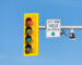 Close-up of a traffic signal and regulatory sign under blue sky.