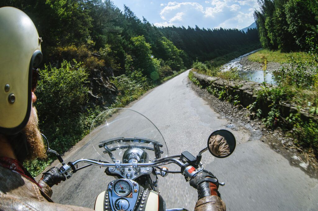 Biker in helmet driving his motorcycle on the open road by the river.