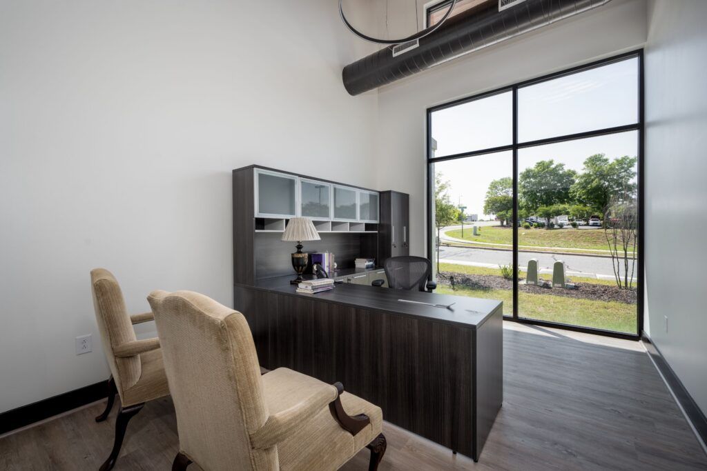 Reception desk with black cabinetry, cream seating, and glass partition door overlooking grounds