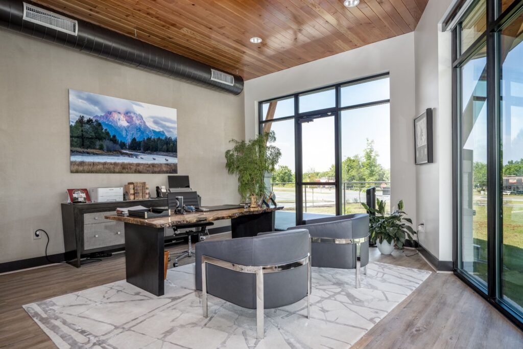 Executive office with live-edge desk, black cabinetry, mountain landscape artwork, and glass doors