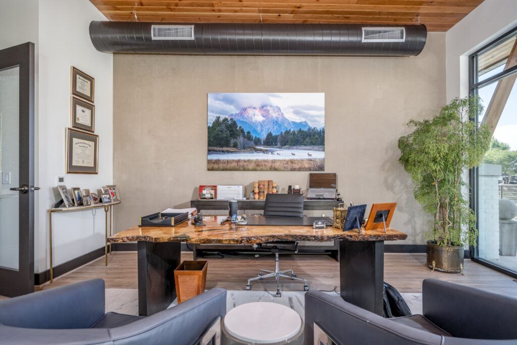 Karney Clayton private office with live-edge wood desk and mountain landscape art