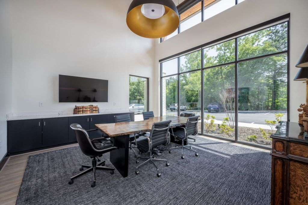 Modern office meeting room with wall-mounted TV, wood table, and floor-to-ceiling windows