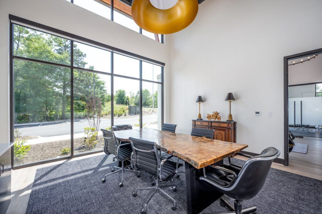 Contemporary conference room with live-edge wood table, large windows, and golden pendant lighting