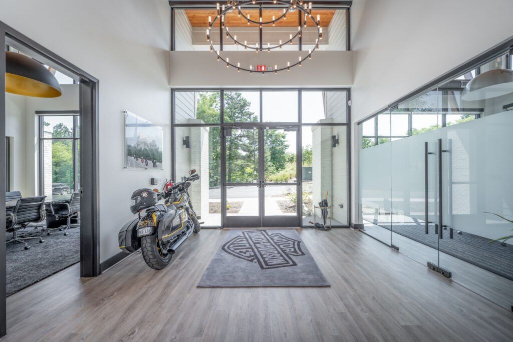 Modern office entryway with motorcycle display, wood ceiling, pendant lighting, and glass doors