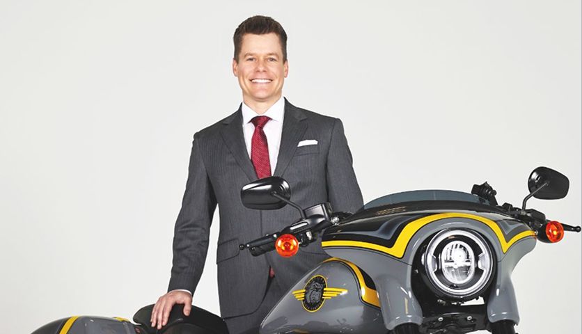 Karney Clayton attorney in gray pinstripe suit with custom black and yellow motorcycle.