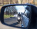Motorcycle passing a vehicle seen in a side mirror, illustrating the risks of distracted and improper driving for motorcyclists in North Carolina