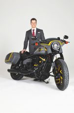 Karney Clayton attorney in gray pinstripe suit with custom black and yellow motorcycle.
